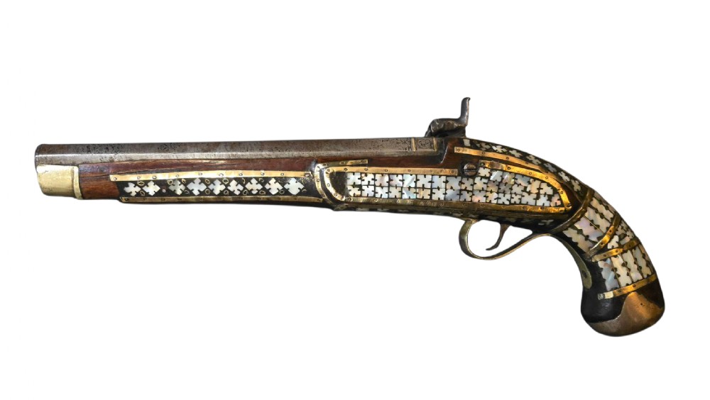 A 19th-century Ottoman pistol featuring a dark wood stock inlaid with mother-of-pearl geometric designs and brass wire, with an engraved steel mechanism and barrel. View X