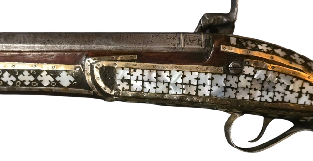 A 19th-century Ottoman pistol featuring a dark wood stock inlaid with mother-of-pearl geometric designs and brass wire, with an engraved steel mechanism and barrel. View XII