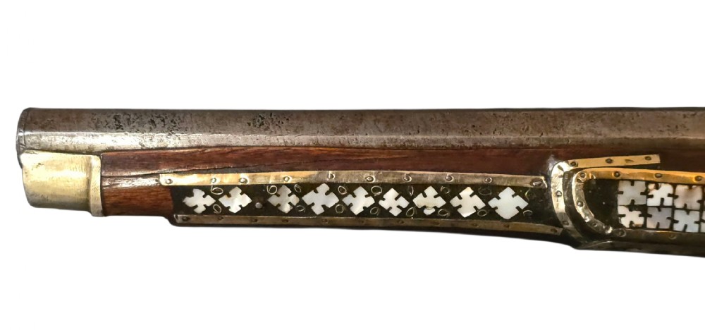 A 19th-century Ottoman pistol featuring a dark wood stock inlaid with mother-of-pearl geometric designs and brass wire, with an engraved steel mechanism and barrel. View XIII