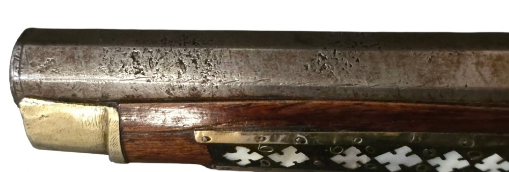 A 19th-century Ottoman pistol featuring a dark wood stock inlaid with mother-of-pearl geometric designs and brass wire, with an engraved steel mechanism and barrel. View XV