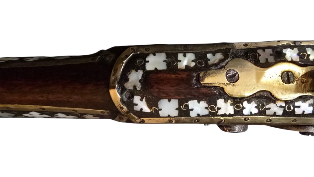 A 19th-century Ottoman pistol featuring a dark wood stock inlaid with mother-of-pearl geometric designs and brass wire, with an engraved steel mechanism and barrel. View XXII