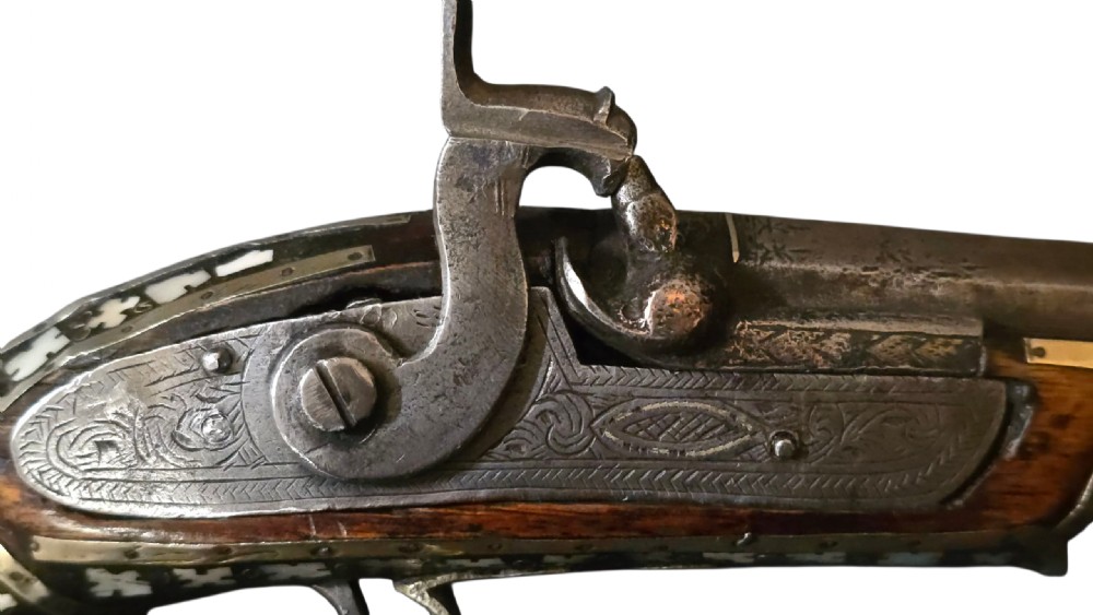 A 19th-century Ottoman pistol featuring a dark wood stock inlaid with mother-of-pearl geometric designs and brass wire, with an engraved steel mechanism and barrel. View XXIV