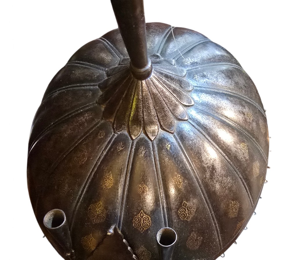 An 18th-century Indian steel Kulah Khud helmet featuring gold inlay detailing, a sliding nasal guard, a tall plume with white and green hair, and a hanging chainmail aventail. View IX