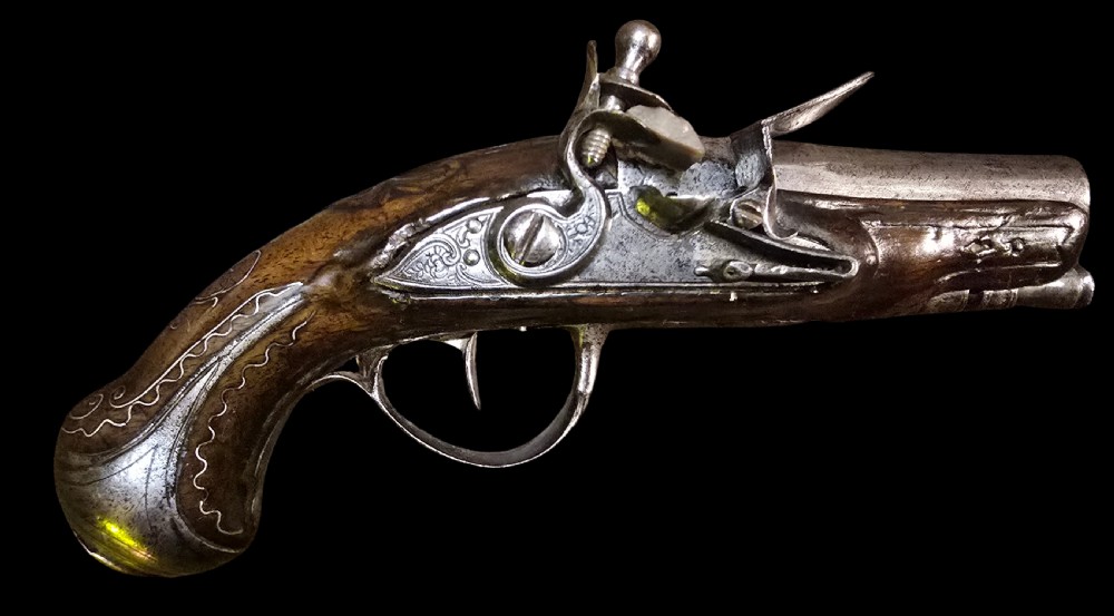 A small mid-18th century French flintlock muff pistol with a dark walnut stock featuring silver wire scroll inlay and an engraved steel lock mechanism.
