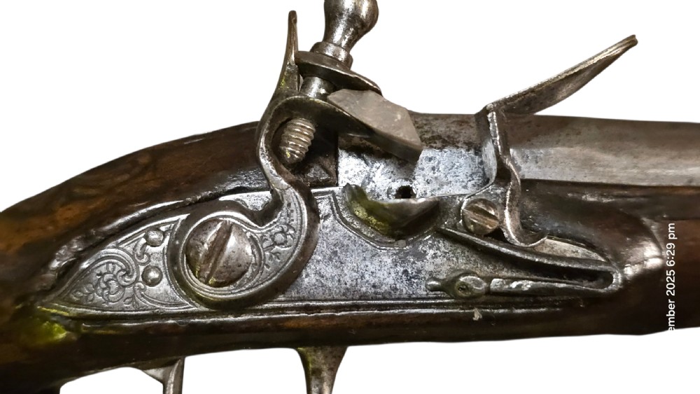 A small mid-18th century French flintlock muff pistol with a dark walnut stock featuring silver wire scroll inlay and an engraved steel lock mechanism. View II