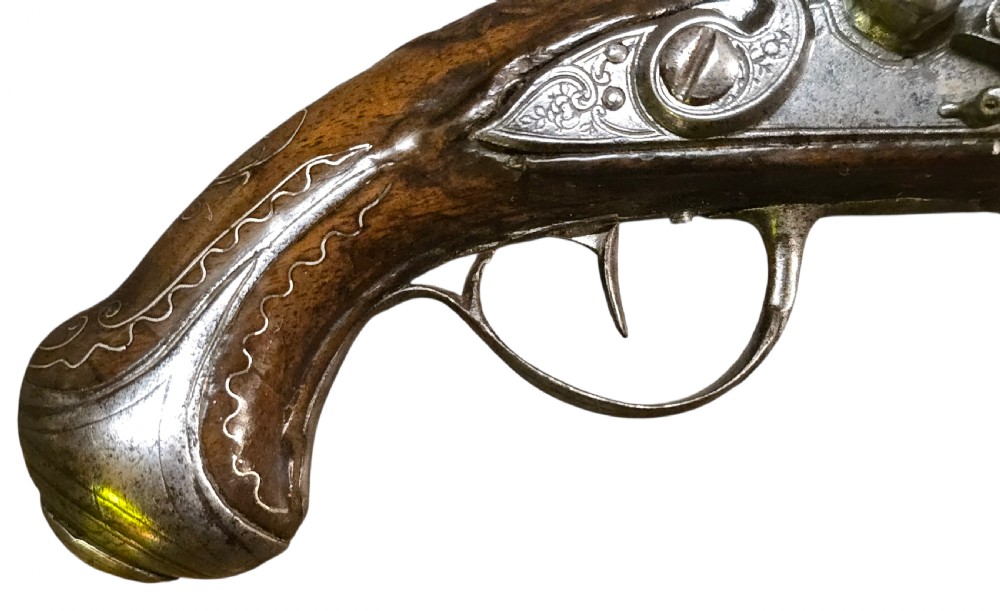 A small mid-18th century French flintlock muff pistol with a dark walnut stock featuring silver wire scroll inlay and an engraved steel lock mechanism. View IV