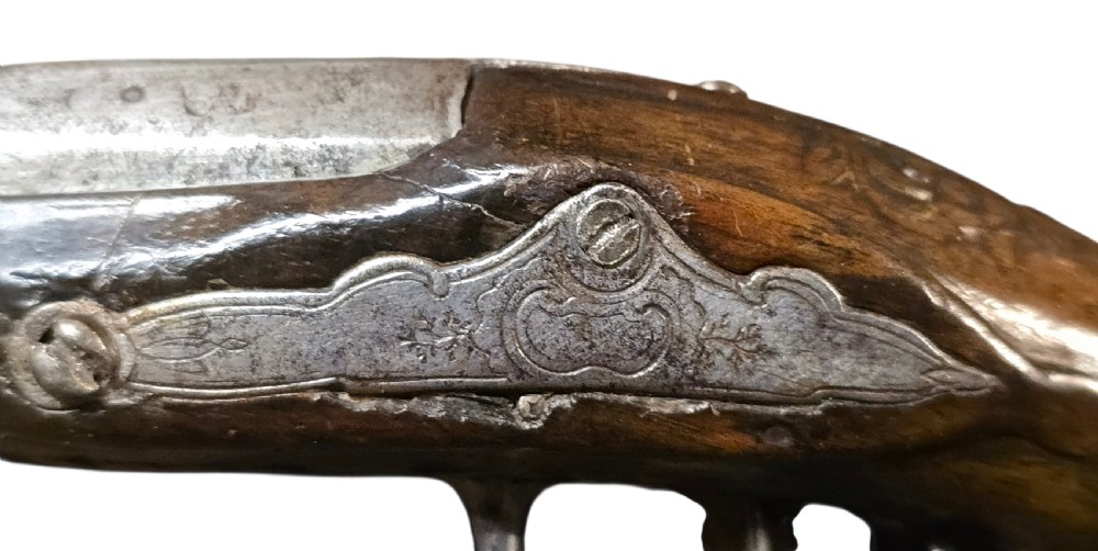A small mid-18th century French flintlock muff pistol with a dark walnut stock featuring silver wire scroll inlay and an engraved steel lock mechanism. View XI