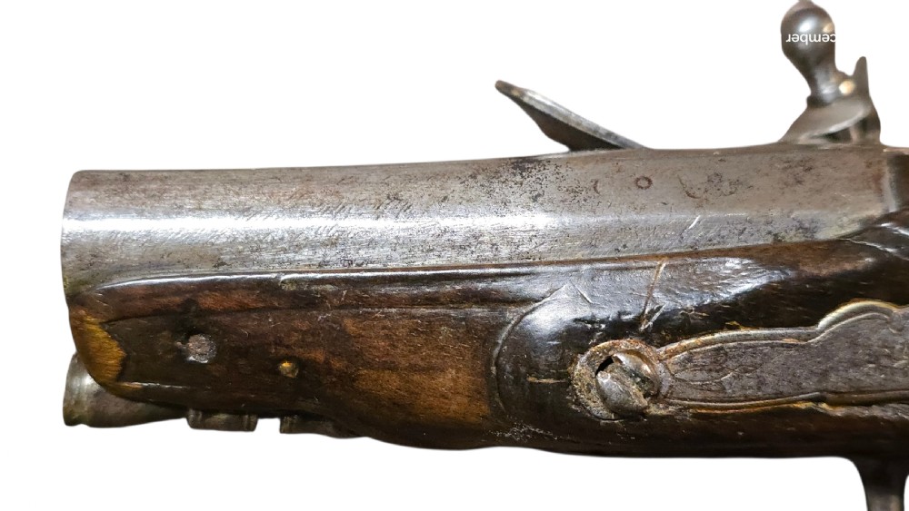 A small mid-18th century French flintlock muff pistol with a dark walnut stock featuring silver wire scroll inlay and an engraved steel lock mechanism. View XII