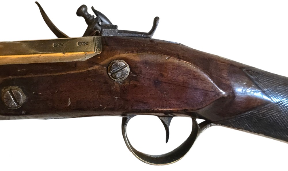 Late eighteenth-century British flintlock blunderbuss featuring a flared brass barrel, dark polished walnut stock, steel flintlock action, top-mounted sprung bayonet, and a separate wooden ramrod. View XII