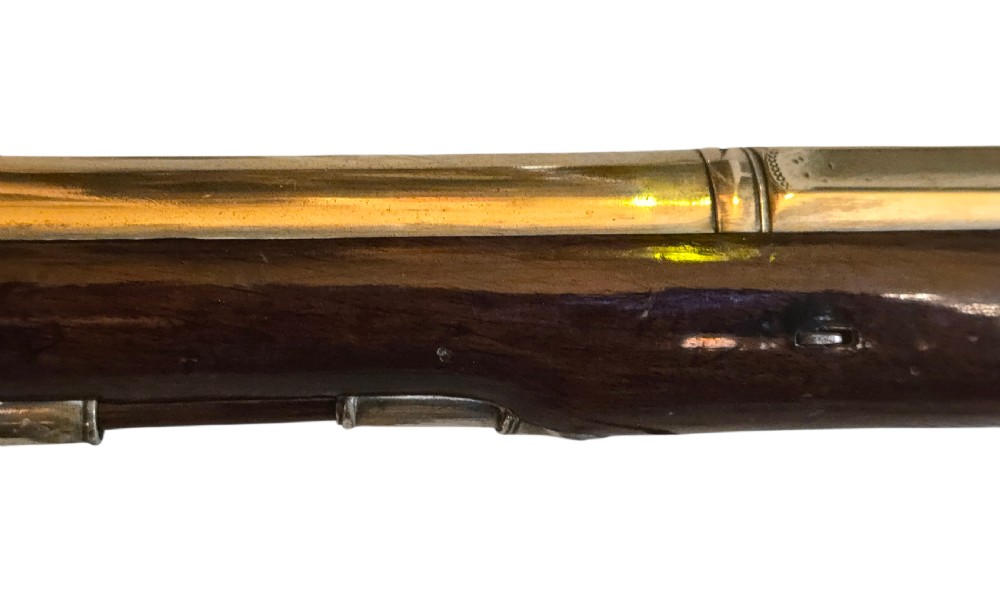 Late eighteenth-century British flintlock blunderbuss featuring a flared brass barrel, dark polished walnut stock, steel flintlock action, top-mounted sprung bayonet, and a separate wooden ramrod. View XIII