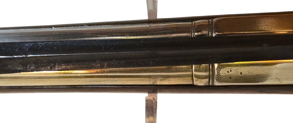 Late eighteenth-century British flintlock blunderbuss featuring a flared brass barrel, dark polished walnut stock, steel flintlock action, top-mounted sprung bayonet, and a separate wooden ramrod. View XXI
