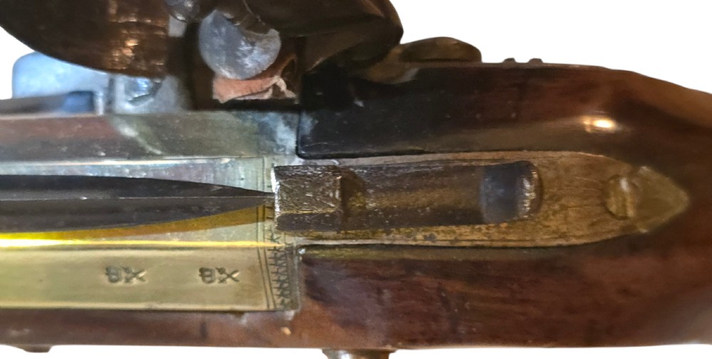 Late eighteenth-century British flintlock blunderbuss featuring a flared brass barrel, dark polished walnut stock, steel flintlock action, top-mounted sprung bayonet, and a separate wooden ramrod. View XXII