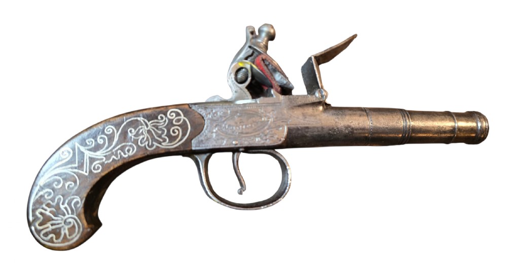 An 18th-century English flintlock pocket pistol featuring a steel cannon barrel, engraved action, and a dark wooden grip with inlaid silver wire scrollwork. View II