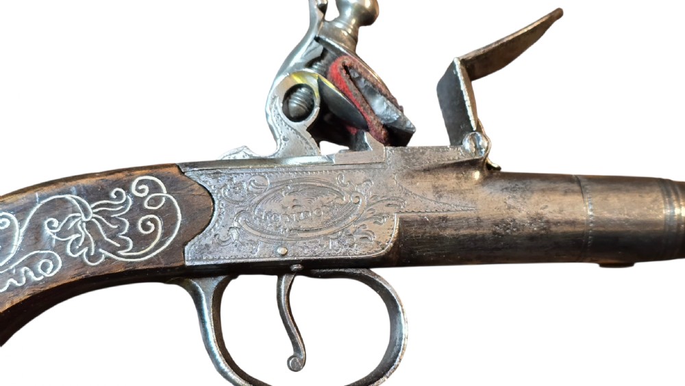 An 18th-century English flintlock pocket pistol featuring a steel cannon barrel, engraved action, and a dark wooden grip with inlaid silver wire scrollwork. View III