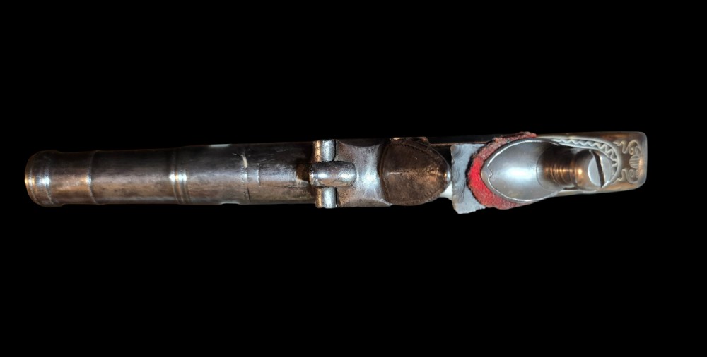 An 18th-century English flintlock pocket pistol featuring a steel cannon barrel, engraved action, and a dark wooden grip with inlaid silver wire scrollwork. View XII