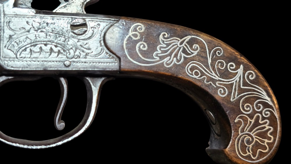 An 18th-century English flintlock pocket pistol featuring a steel cannon barrel, engraved action, and a dark wooden grip with inlaid silver wire scrollwork. View XVI