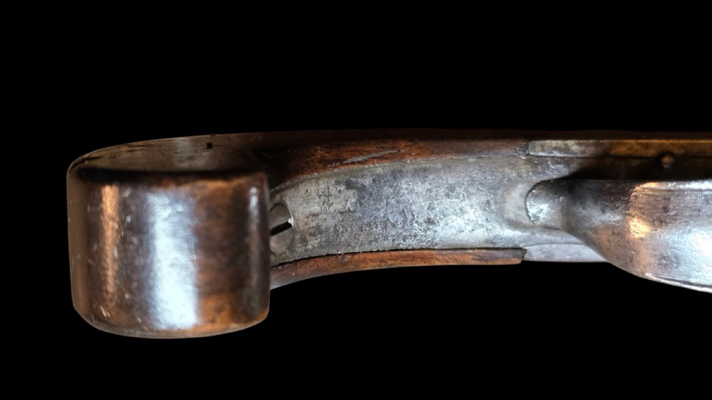 An 18th-century English flintlock pocket pistol featuring a steel cannon barrel, engraved action, and a dark wooden grip with inlaid silver wire scrollwork. View XVII