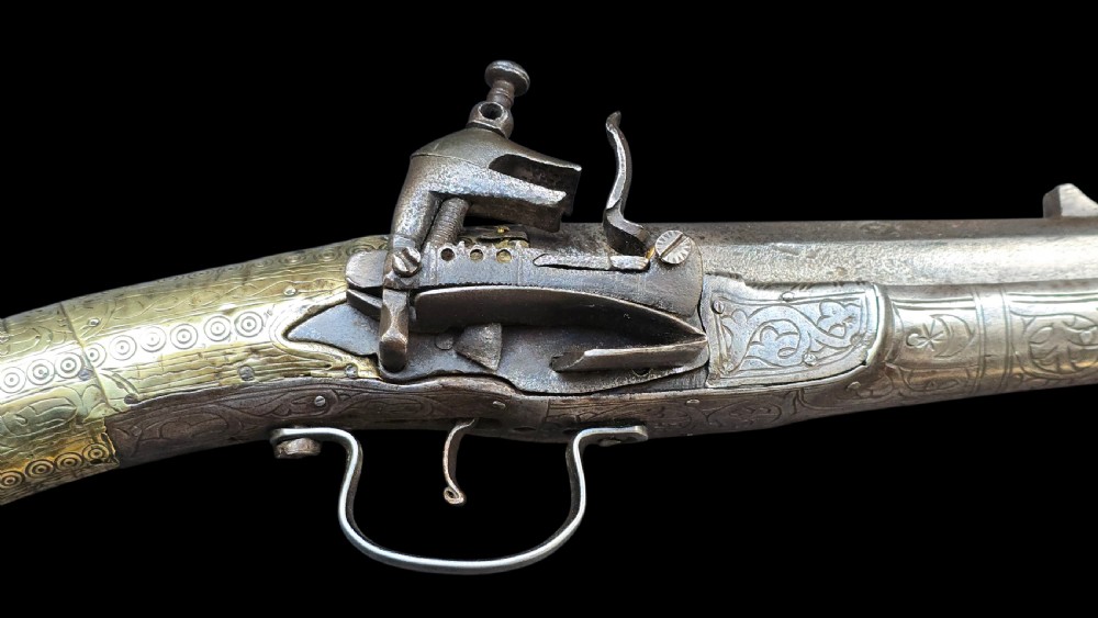 An eighteenth-century Ottoman Balkan flintlock musket carbine with a brass-sheathed stock featuring chased geometric patterns and a steel barrel. View III