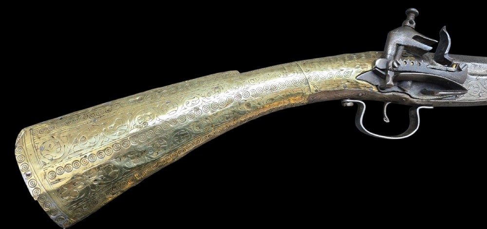An eighteenth-century Ottoman Balkan flintlock musket carbine with a brass-sheathed stock featuring chased geometric patterns and a steel barrel. View XVII