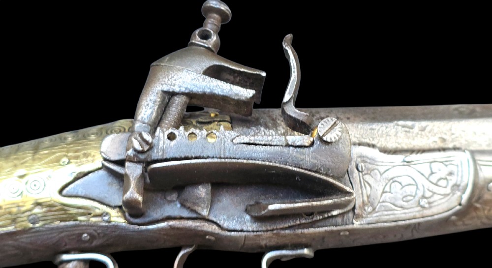 An eighteenth-century Ottoman Balkan flintlock musket carbine with a brass-sheathed stock featuring chased geometric patterns and a steel barrel. View XXII