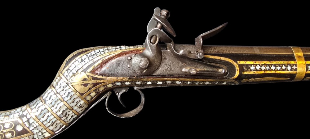 A late 18th-century Indo-Persian flintlock musket featuring a curved wooden stock inlaid with mother-of-pearl geometric patterns and bound with brass barrel bands. View II