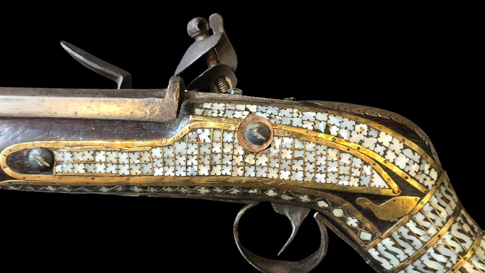 A late 18th-century Indo-Persian flintlock musket featuring a curved wooden stock inlaid with mother-of-pearl geometric patterns and bound with brass barrel bands. View III