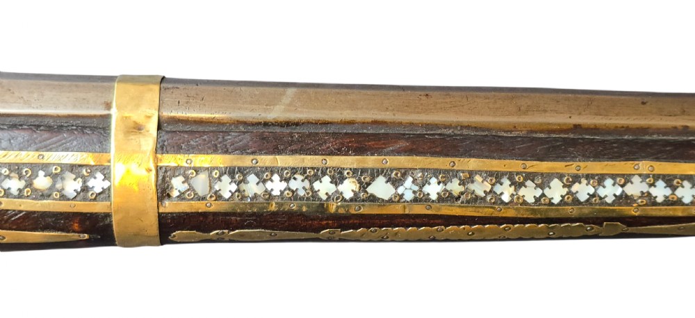 A late 18th-century Indo-Persian flintlock musket featuring a curved wooden stock inlaid with mother-of-pearl geometric patterns and bound with brass barrel bands. View X
