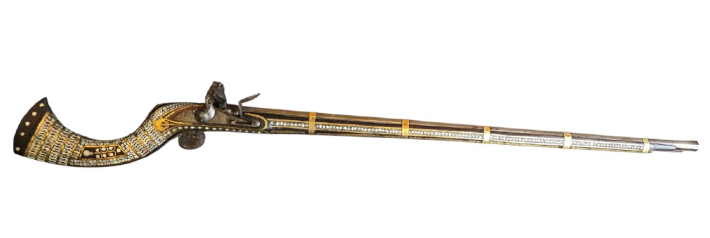 A late 18th-century Indo-Persian flintlock musket featuring a curved wooden stock inlaid with mother-of-pearl geometric patterns and bound with brass barrel bands. View XIX