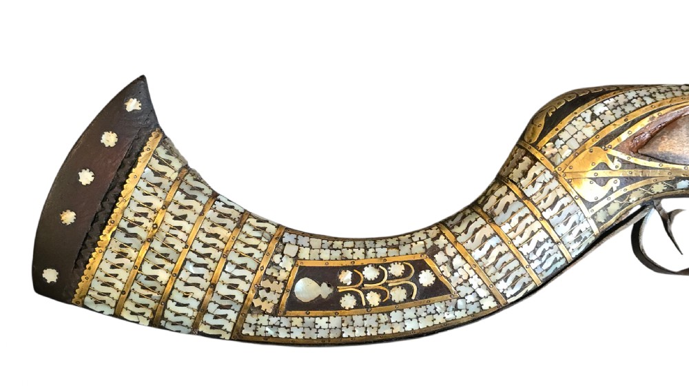 A late 18th-century Indo-Persian flintlock musket featuring a curved wooden stock inlaid with mother-of-pearl geometric patterns and bound with brass barrel bands. View XX