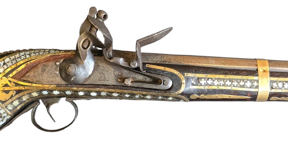 A late 18th-century Indo-Persian flintlock musket featuring a curved wooden stock inlaid with mother-of-pearl geometric patterns and bound with brass barrel bands. View XXII