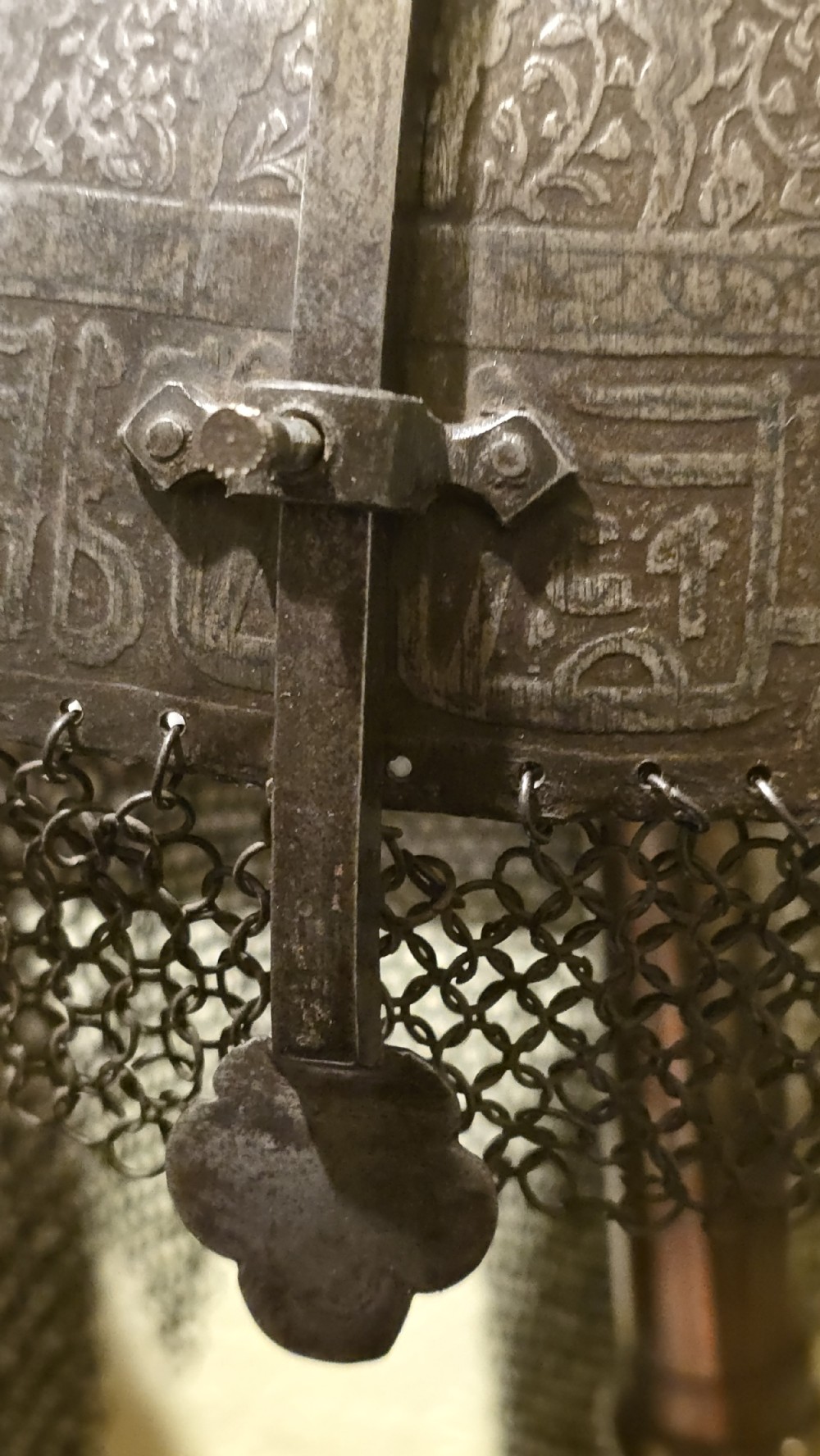 An antique steel Indo-Persian Kullah Khud helmet featuring a central top spike, engraved calligraphic rim, sliding nasal guard, and hanging chainmail aventail mounted on a display stand. View XV