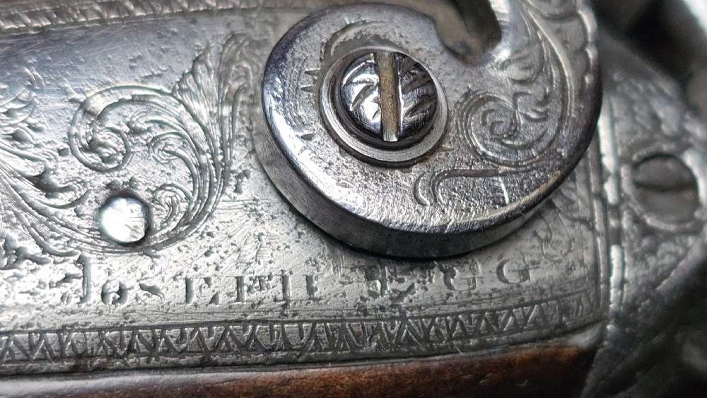 An open mahogany presentation case lined with red velvet, containing a single saw-handled percussion target pistol alongside loading accessories. View III