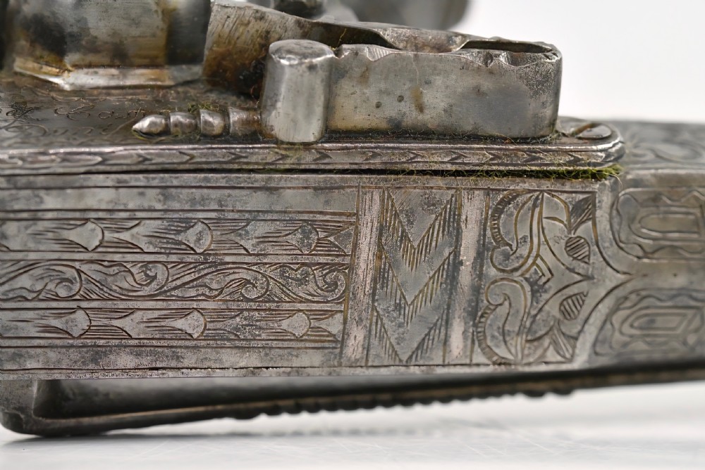 An 18th-century Scottish all-steel scroll-butt flintlock pistol with intricate surface engravings and a ramshorn terminal. View VII