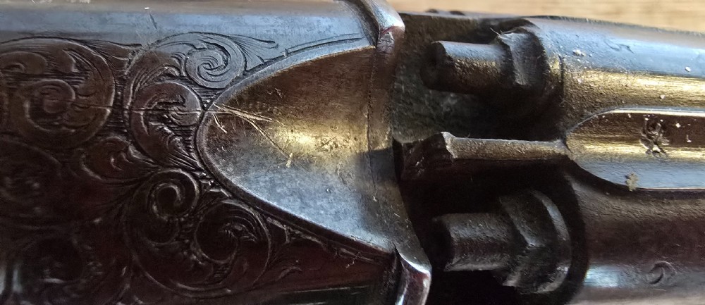 A nineteenth-century six-shot percussion pepperbox pistol featuring a multi-barrel steel cylinder, engraved frame, ring trigger, and chequered dark wood grip. View XVII