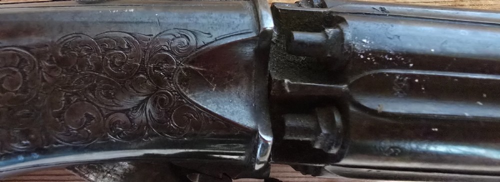 A nineteenth-century six-shot percussion pepperbox pistol featuring a multi-barrel steel cylinder, engraved frame, ring trigger, and chequered dark wood grip. View XIX