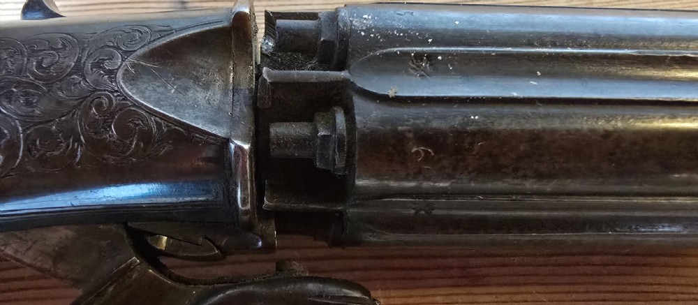 A nineteenth-century six-shot percussion pepperbox pistol featuring a multi-barrel steel cylinder, engraved frame, ring trigger, and chequered dark wood grip. View XX