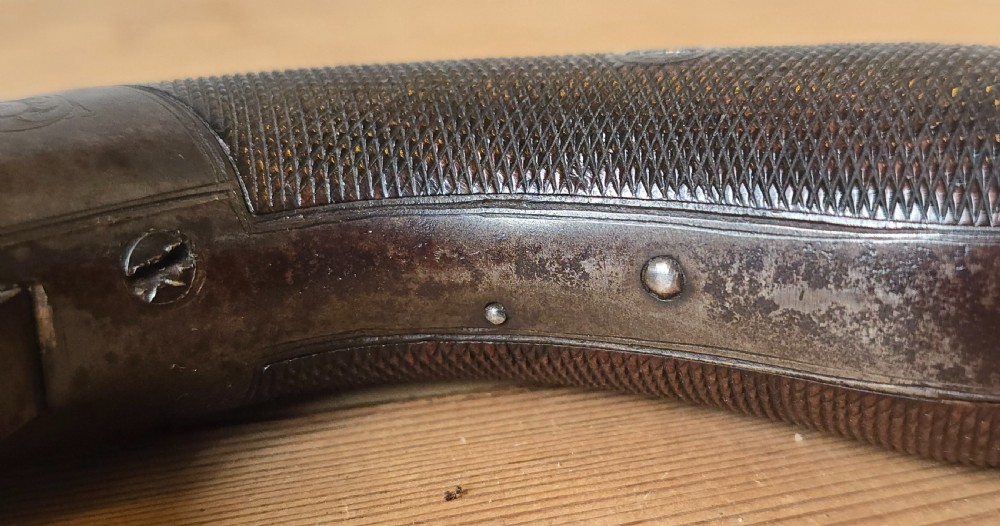 A nineteenth-century six-shot percussion pepperbox pistol featuring a multi-barrel steel cylinder, engraved frame, ring trigger, and chequered dark wood grip. View XXIV