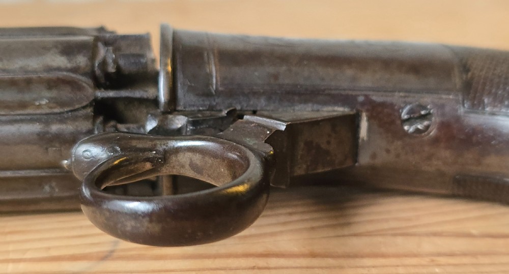 A nineteenth-century six-shot percussion pepperbox pistol featuring a multi-barrel steel cylinder, engraved frame, ring trigger, and chequered dark wood grip. View XXV