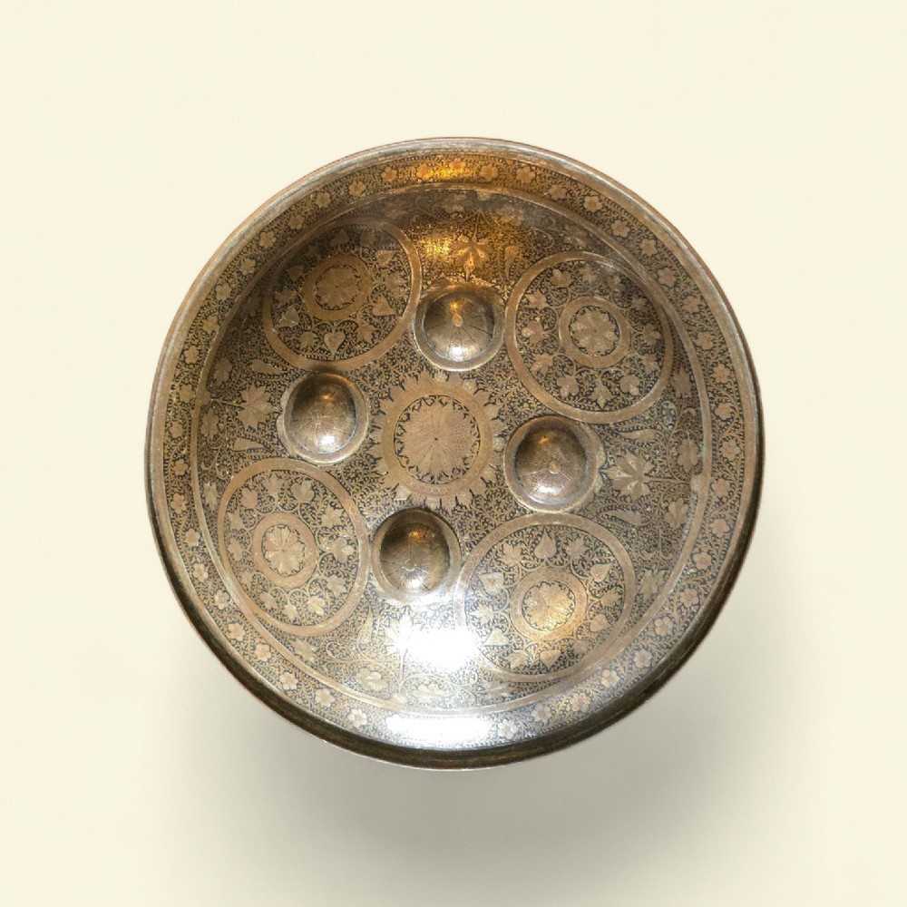 A circular late 19th-century Indian brass dhal shield featuring four central raised bosses and detailed engraved foliate patterns.