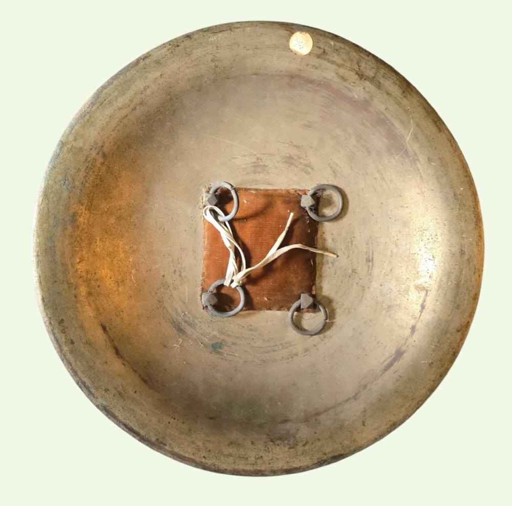 A circular late 19th-century Indian brass dhal shield featuring four central raised bosses and detailed engraved foliate patterns. View II