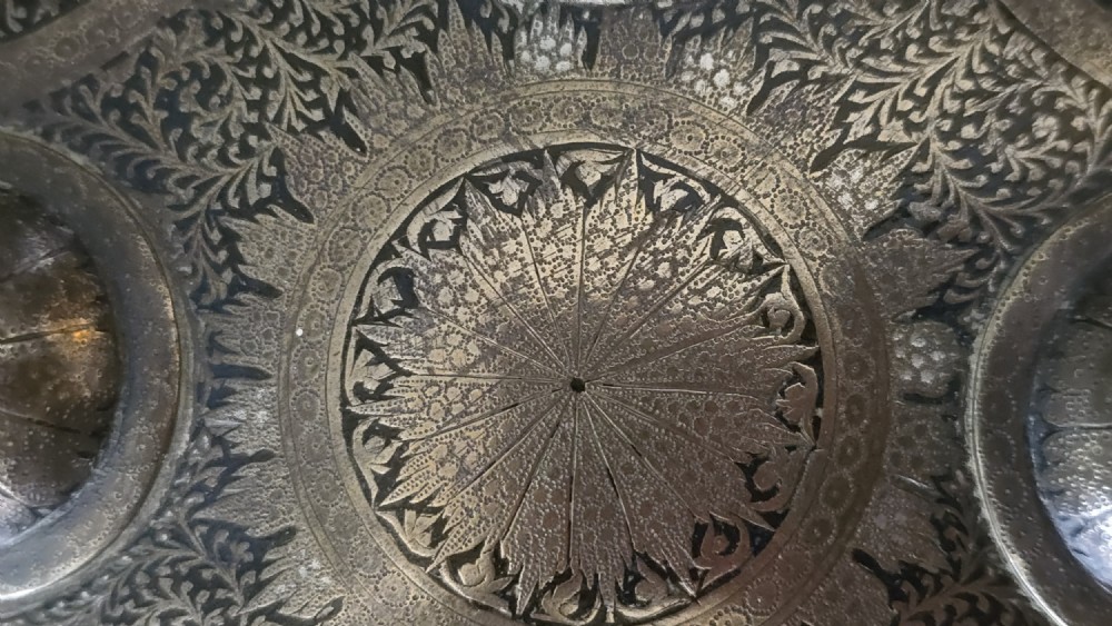 A circular late 19th-century Indian brass dhal shield featuring four central raised bosses and detailed engraved foliate patterns. View VII