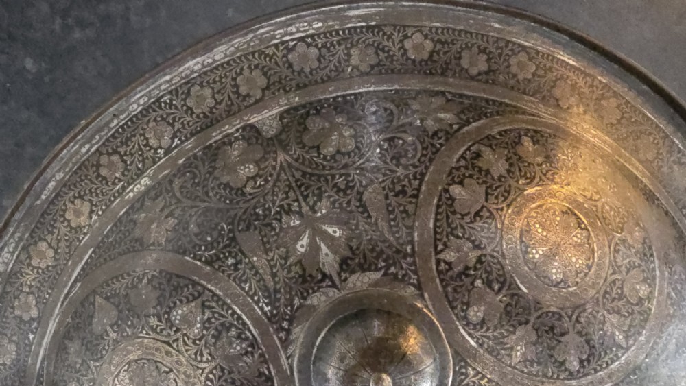 A circular late 19th-century Indian brass dhal shield featuring four central raised bosses and detailed engraved foliate patterns. View VIII