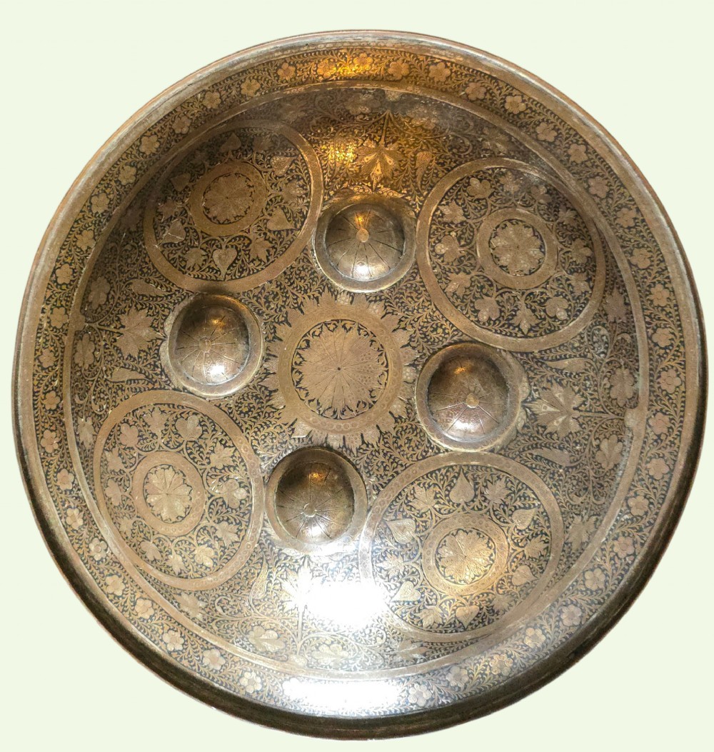 A circular late 19th-century Indian brass dhal shield featuring four central raised bosses and detailed engraved foliate patterns. View XV