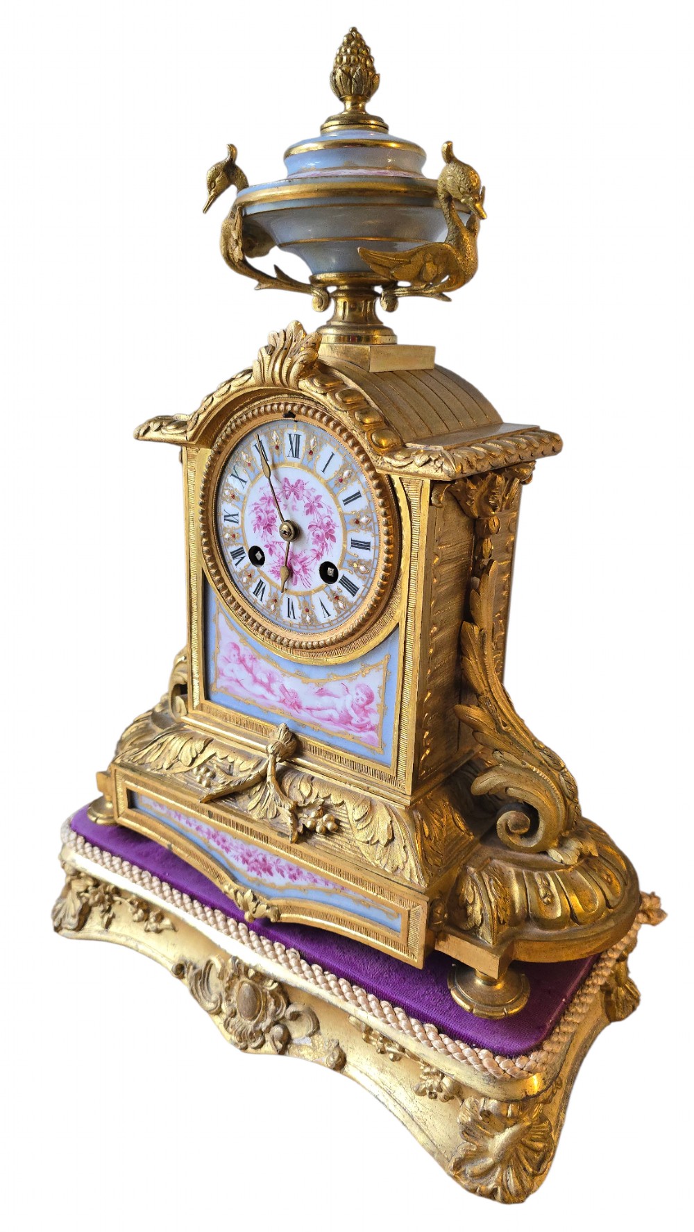 A French gilt bronze mantel clock decorated with hand-painted pink floral and cherub porcelain panels and topped with an urn flanked by swan handles. View III