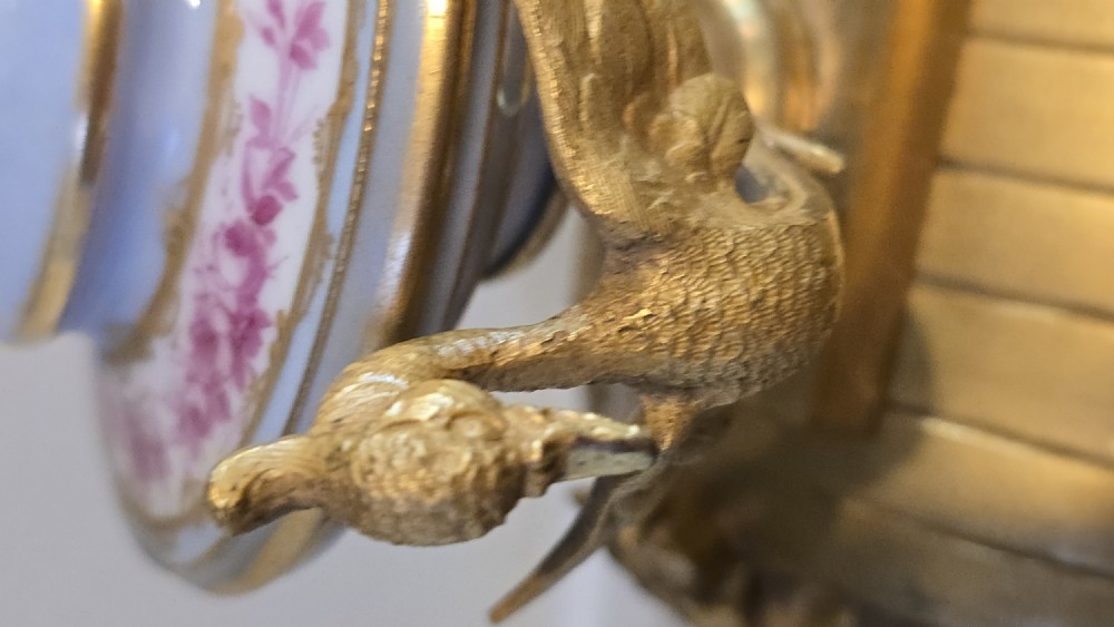 A French gilt bronze mantel clock decorated with hand-painted pink floral and cherub porcelain panels and topped with an urn flanked by swan handles. View VIII
