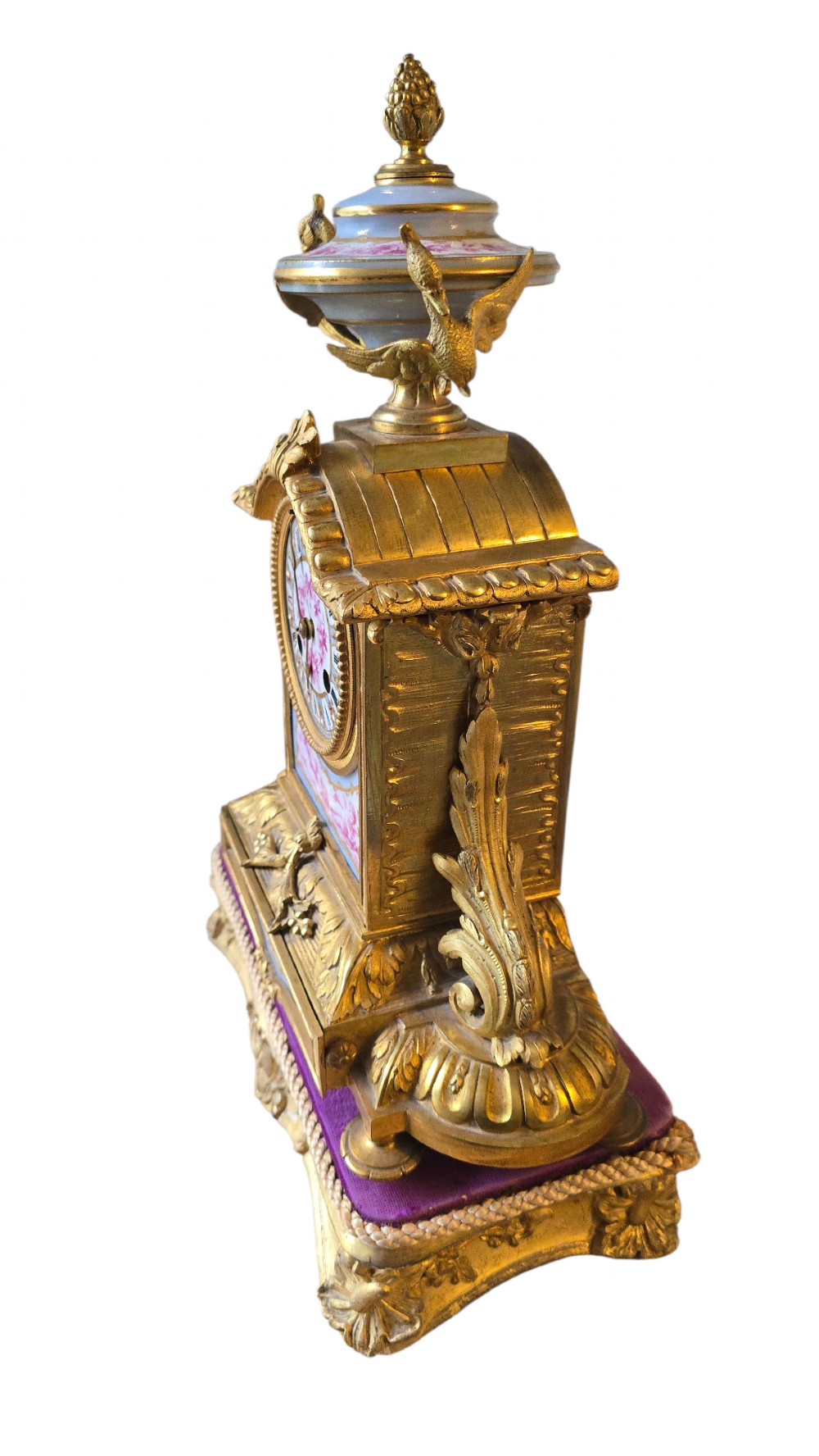 A French gilt bronze mantel clock decorated with hand-painted pink floral and cherub porcelain panels and topped with an urn flanked by swan handles. View XI