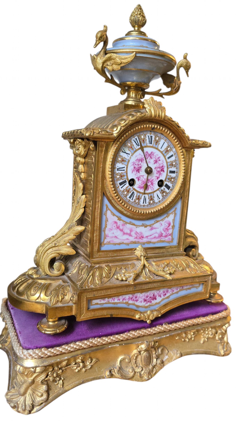 A French gilt bronze mantel clock decorated with hand-painted pink floral and cherub porcelain panels and topped with an urn flanked by swan handles. View XIII