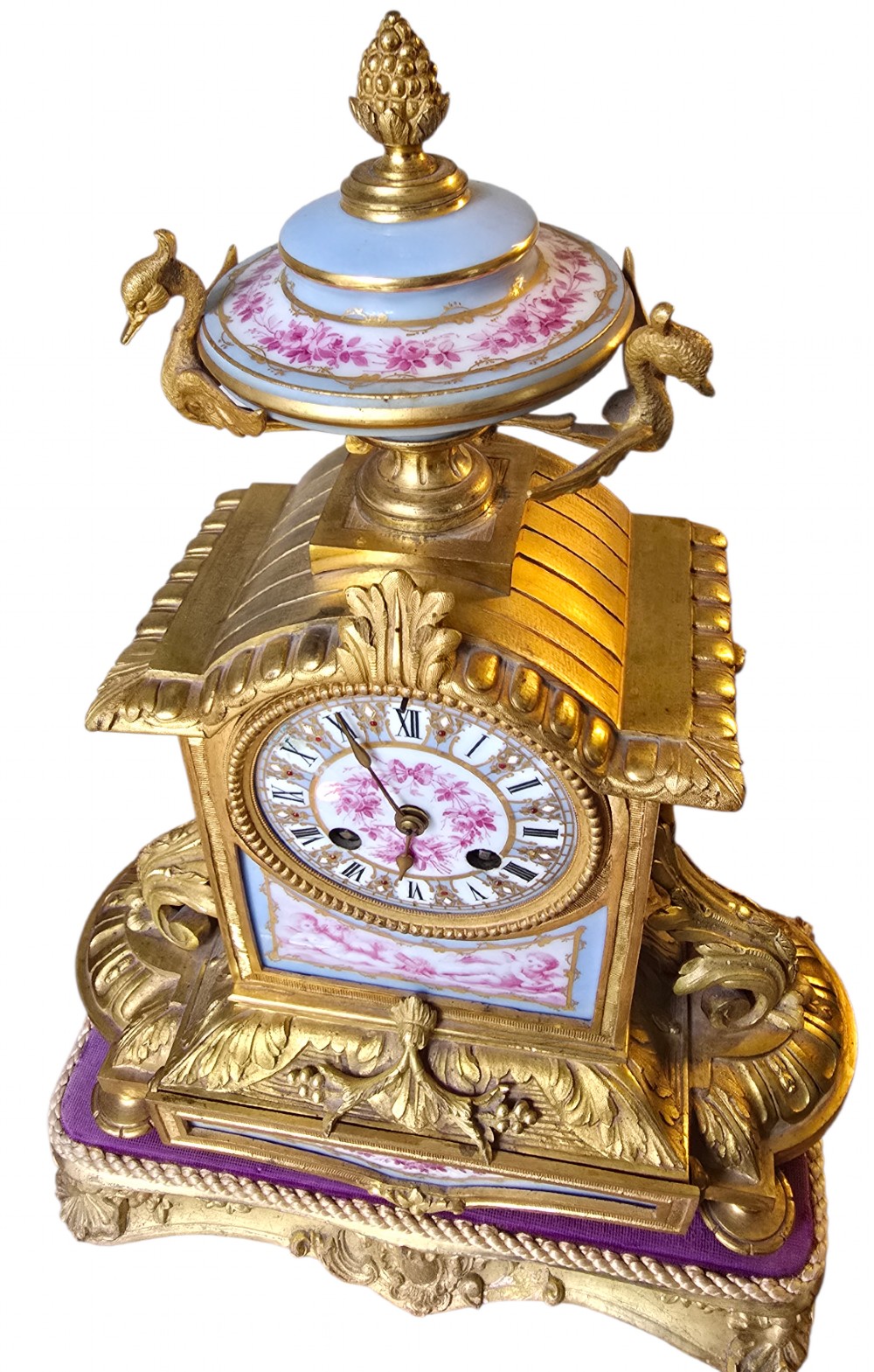 A French gilt bronze mantel clock decorated with hand-painted pink floral and cherub porcelain panels and topped with an urn flanked by swan handles. View XV