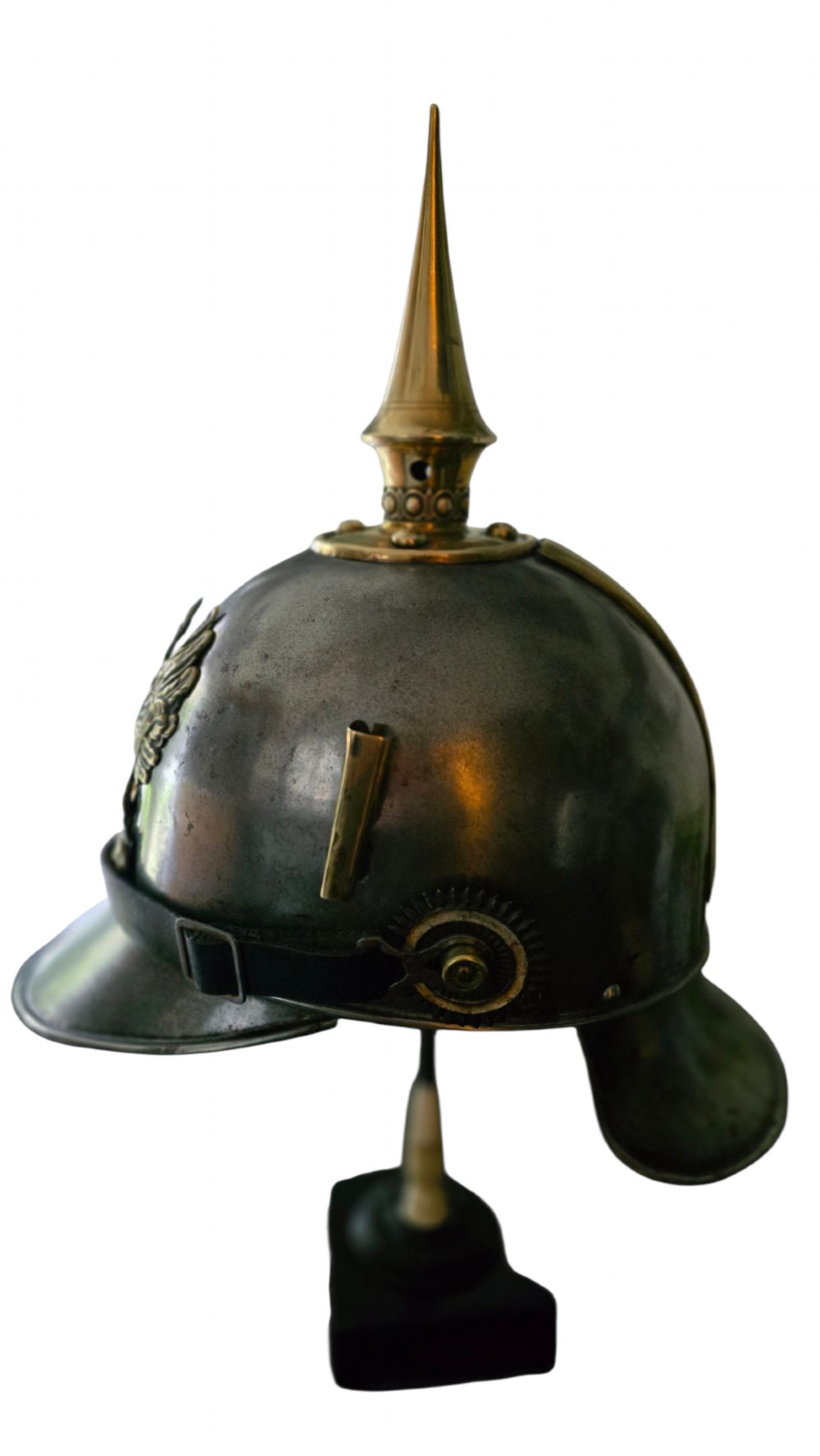 A WWI Prussian steel Pickelhaube helmet featuring a brass spiked top, a brass Prussian eagle emblem on the front, and a black strap. View III