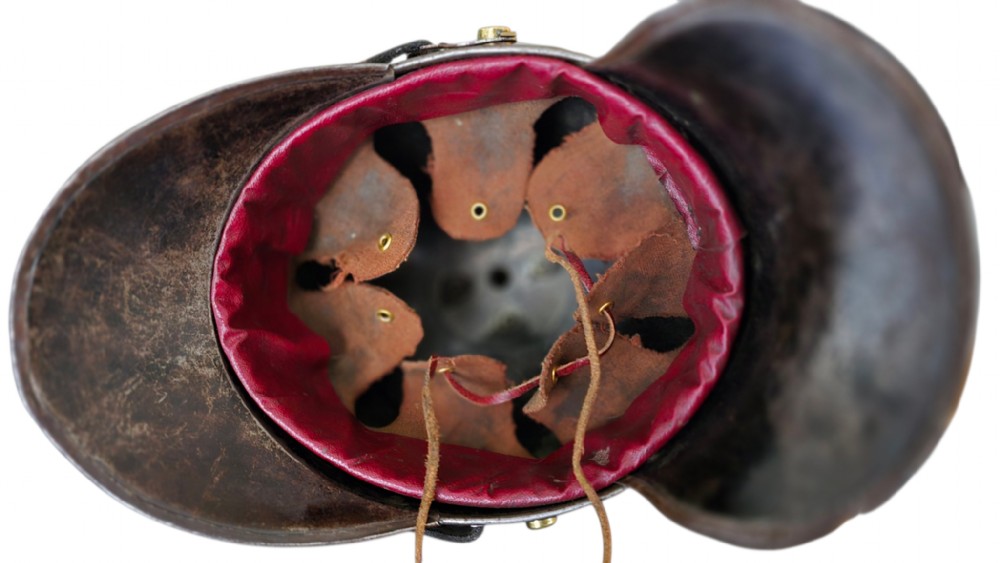 A WWI Prussian steel Pickelhaube helmet featuring a brass spiked top, a brass Prussian eagle emblem on the front, and a black strap. View V